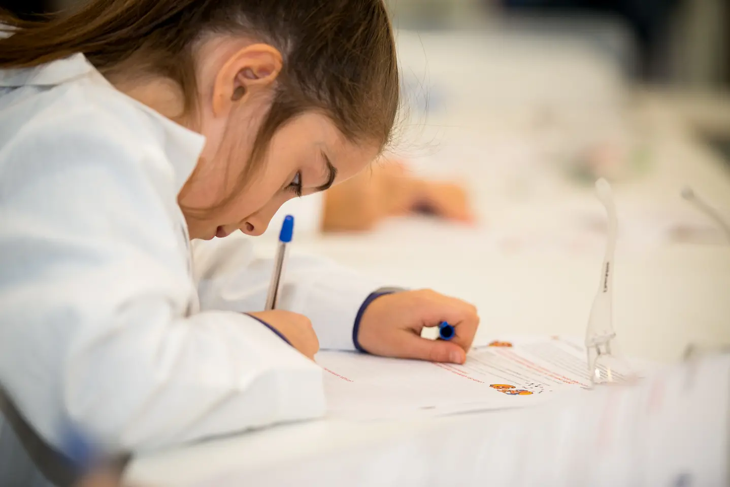 dziewczynka pisząca w laboratorium na papierze
