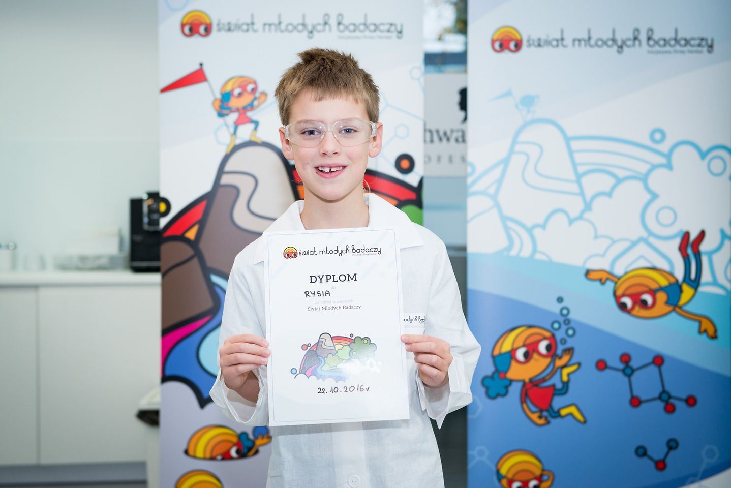 Chłopiec trzymający dyplom Świata Młodych Badaczy