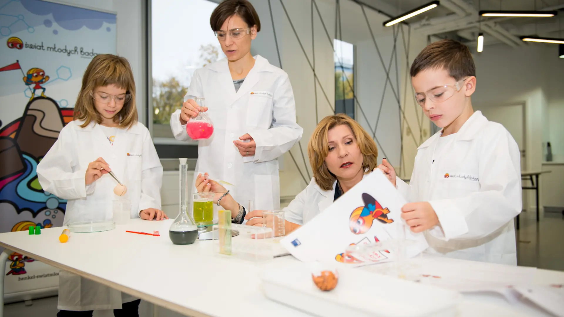 dwoje dzieci i dwoje dorosłych przeprowadzających doświadczenia w laboratorium
